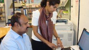 Volunteer Sahar Rai helps library user Krishnapillai Preamkumar