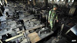 A soldier walks through the site of fire at Tazreen Fashions plant near Dhaka, 26 November 2012