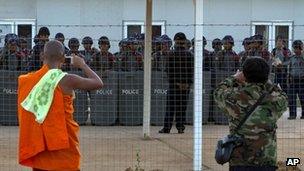 A protesting Buddhist monk and a man take pictures of Burmese police at the Letpadaung mine, Monywa, 28 November 2012
