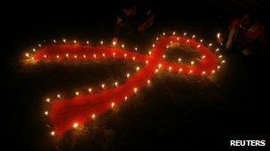 Red ribbon symbol and candles in India for World Aids Day