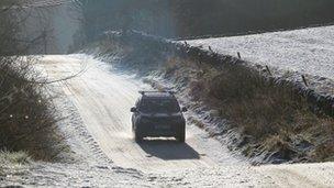 A vehicle drives along a snow covered road in the Scottish Borders