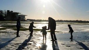 People walk on frozen flood water at York Racecourse, England