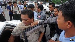 Myanmar police (back R) arrest protester Aung Soe (L) and put him into a car during a protest in Rangoon on December 2, 2012.