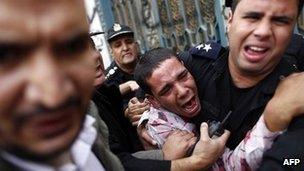 An opposition protester is helped by police in Cairo (5 Dec 2012)