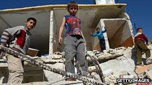 Syrian children play on the rubble of buildings
