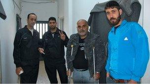 Four residents of Cyber City camp stand in the corridor including Jihad Khalil (with crutches)