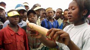 An educator shows how to use a condom in Nairobi, Kenya in December 2001, during International AIDS day.