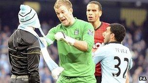 Manchester City's Joe Hart stops a fan who walked onto the pitch to confront Manchester United's Rio Ferdinand