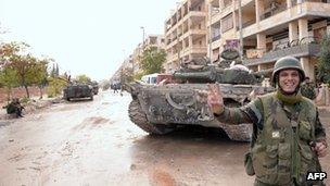 A Syrian army soldier flashes the V-sign for victory as he stands close to tanks in Aleppo. Photo: November 2012