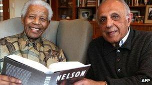 Former South African President Nelson Mandela posing with a copy of the British edition of his book Conversations with Myself with fellow former political prisoner Ahmed Kathrada