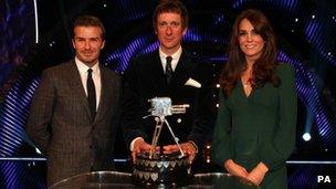 Bradley Wiggins holding the Sports Personality of the Year Trophy on stage with the Duchess of Cambridge and David Beckham