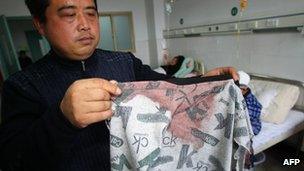 A man displays his son's bloodstained coat in Guangshan, Henan, on 16 December 2012