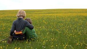 Two young brothers sit beside each other in a field of buttercups