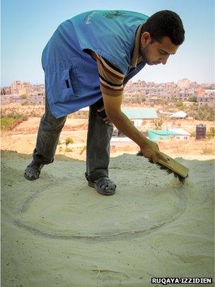 An archaeology student dusts off an ancient oven in Tel Rafah