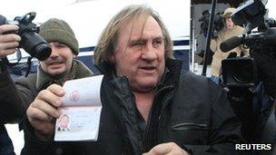 Gerard Depardieu shows his passport after arriving in Moscow