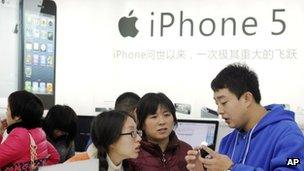 A member of staff talks to customers at an Apple store in China