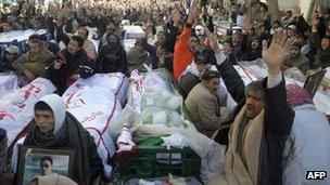 Shia sit between the coffins of bombing victims in Quetta. Photo: 12 January 2013