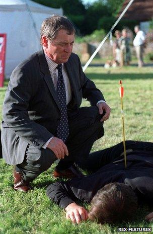 John Nettles examines corpse with arrow in back in Midsomer Murders