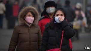 Women cover their noses and mouths while walking in Beijing