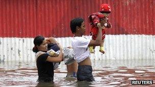 Parents carry their children through flood waters in Jakarta, Indonesia (18 Jan 2013)