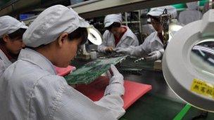 factory workers examine motherboards
