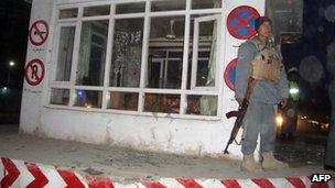 An Afghan policeman stands guard at the site of a suicide attack in Kunduz