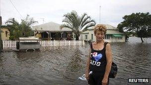 A residents stands in front of her flooded home in Bundaberg on 27 January 2013