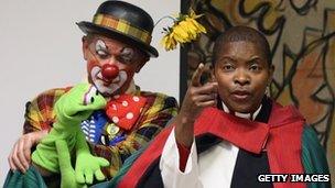 Rev Rose Hudson-Wilkin (R) on stage with clowns in full costume after