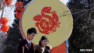 People walk past a Chinese decorative drum with a paper-cutting of a snake ahead of the Chinese Lunar New Year celebrations at Ditan Park in Beijing on 4 February 2013