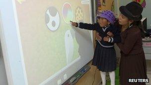 A girl of the village of Zumbahua is learning how to use a large projection touch screen at her school