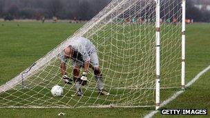Goalkeeper fishes a ball out of the back of the net