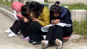 Girls on mobiles in a park in North Korea