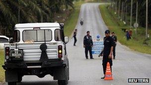 Malaysian policemen man a road block on a street leading to Kampung Tanduo, the area where the armed men are holding off, in Felda Sahabat outside Lahad Datu town on Borneo island 18 February 2013