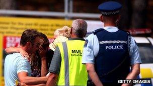 People grieve outside the Muriwai Surf Lifesaving Club after a swimmer died in a fatal shark attack at Muriwai Beach on 27 February 2013 in Auckland, New Zealand
