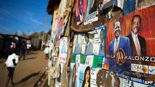 People walk past campaign posters in Nairobi's Kibera slum on 27 February 2013