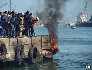 Protesters in Port Said drop a burning tyre into the Suez Canal, 9 March