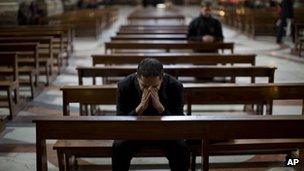 Priest prays at Jesuit Church of St Ignatius in Rome
