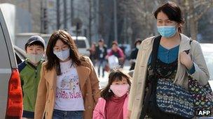 A Chinese family wearing face masks to protect against air pollution walk along a street in Beijing on March 27, 2013.