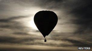A hot air balloon is silhouetted at sunrise