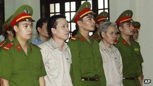 In this April 2, 2013 file photo, Doan Van Vuon, second from left and his brother Doan Van Sinh, fourth from left, stand trial at the court in the northern city of Haiphong, Vietnam.