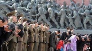 Military personnel salute as civilians bow to giant statues of the late North Korean leaders Kim Il-sung and his son, Kim Jong-il, unseen, in Pyongyang, North Korea, 15 April 2013