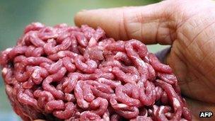 A man holds minced beef meat