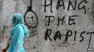 An Indian woman walks past graffiti against rape written on a wall in New Delhi on April 22, 2013.