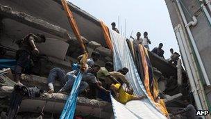 Bangladeshi garment workers assist a survivor onto a length of textile to be used as an evacuation slide