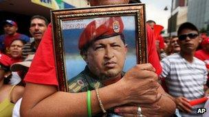 A supporter of Venezuela's President Nicolas Maduro holds a picture of late President Hugo Chavez during Mr Maduro's inauguration in Caracas, Venezuela, on 19 April 2013