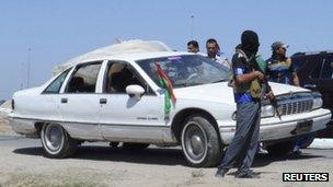 Masked gunman stands next to a vehicle in which three army personnel were killed in Ramadi (27 April 2013)