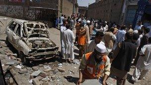 People gather at the site of an explosion outside an election office of a candidate in Peshawar, Pakistan, 28 April 2013
