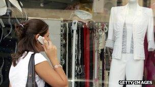 Woman walks past a shop while on the phone