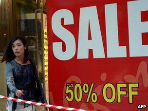 A woman walks past a sale sign in a show window in Sydney