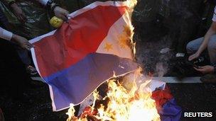 Activists burn Philippine national flags in front of the Manila Economic and Cultural Office, the de facto Philippine embassy in Taiwan, during a protest against the Philippine government in Taipei on 13 May 2013